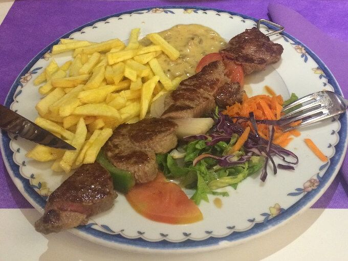 Brocheta de carne con patatas y ensalada